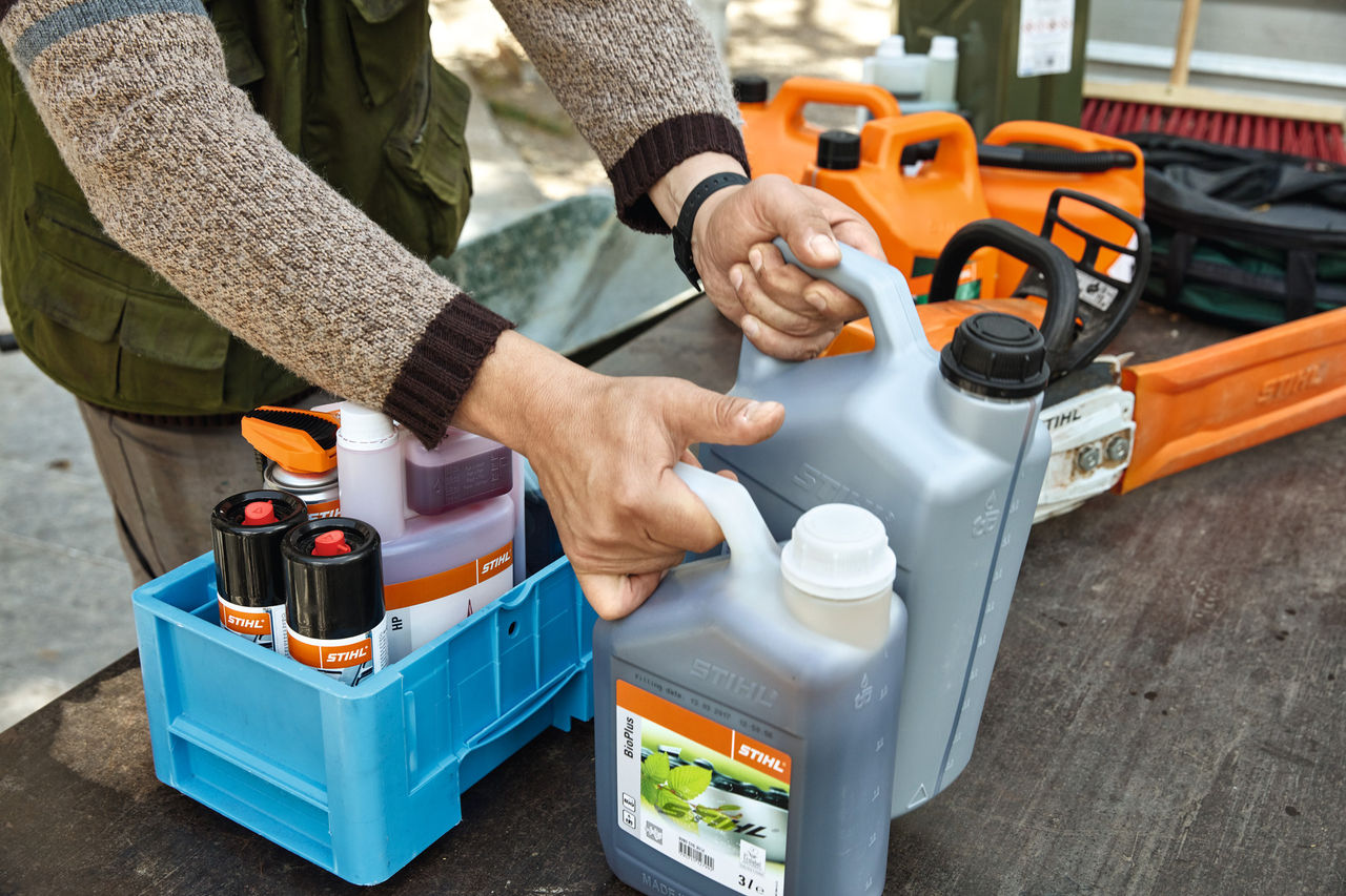 Një person që rregullon karburantet dhe lubrifikantët STIHL në arka për transport 