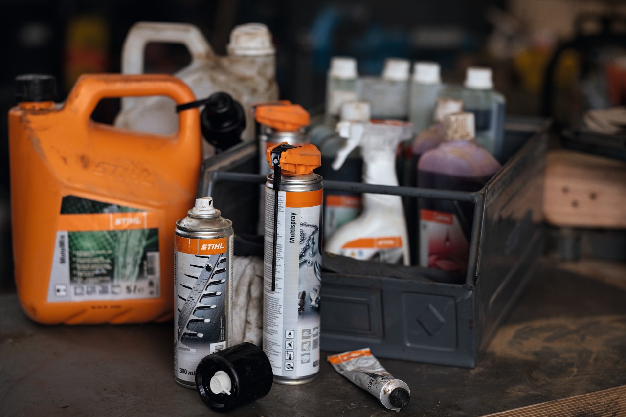 Vajra, lubrifikantë dhe produkte për mirëmbajtjen e pajisjeve STIHL mbi një tavolinë pune.