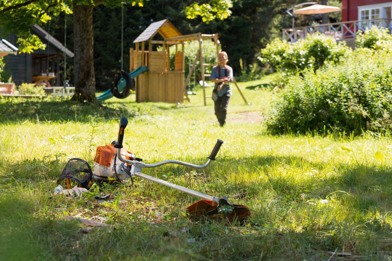 Trimer STIHL FS 240 në bar me një burrë që përgatitet për mirëmbajtje në sfond