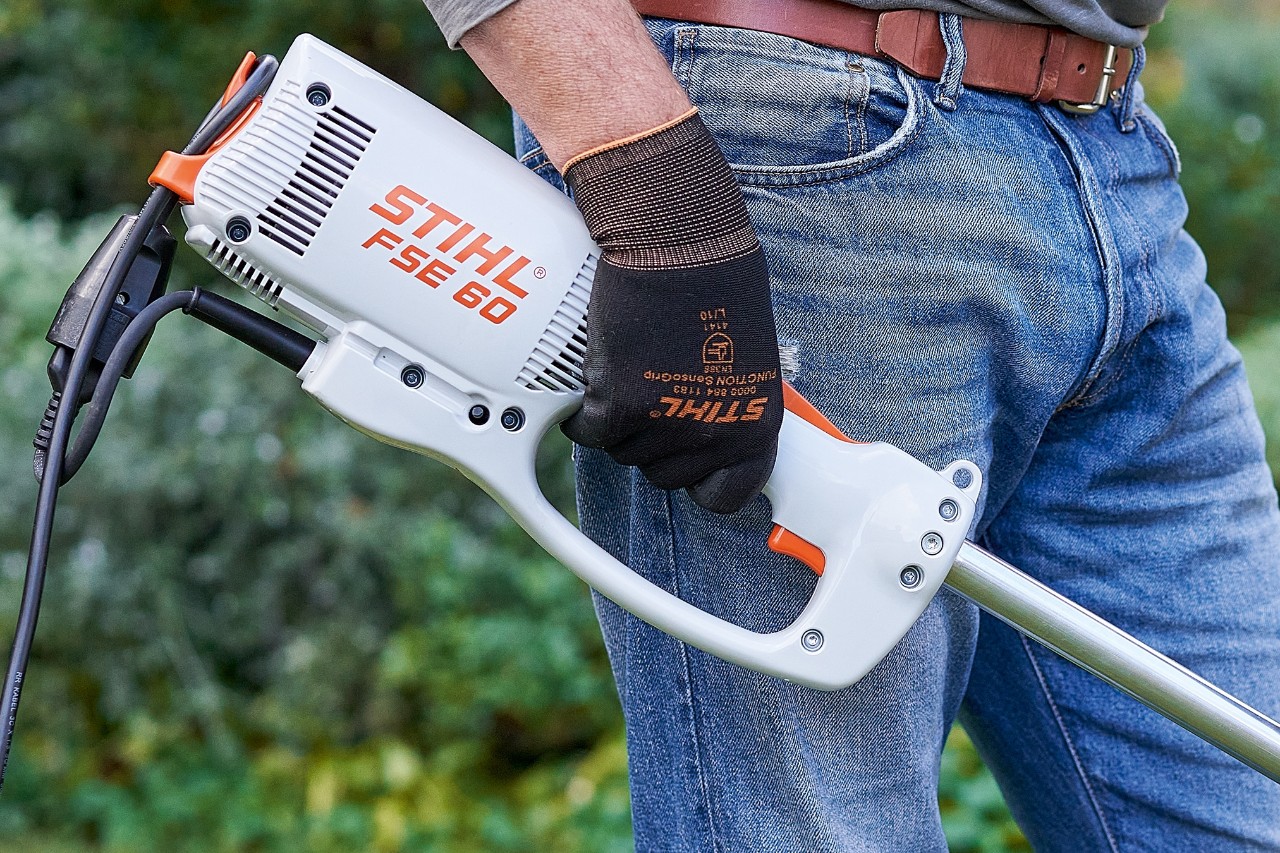Një burrë duke shtypur çelësin për të fikur motokosën elektrike STIHL FSE 60.