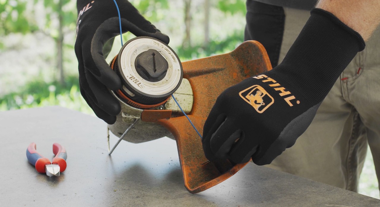 Personi duke mbështjell fijen e kositjes në një krasitëse pa kabllo STIHL FSA 57 