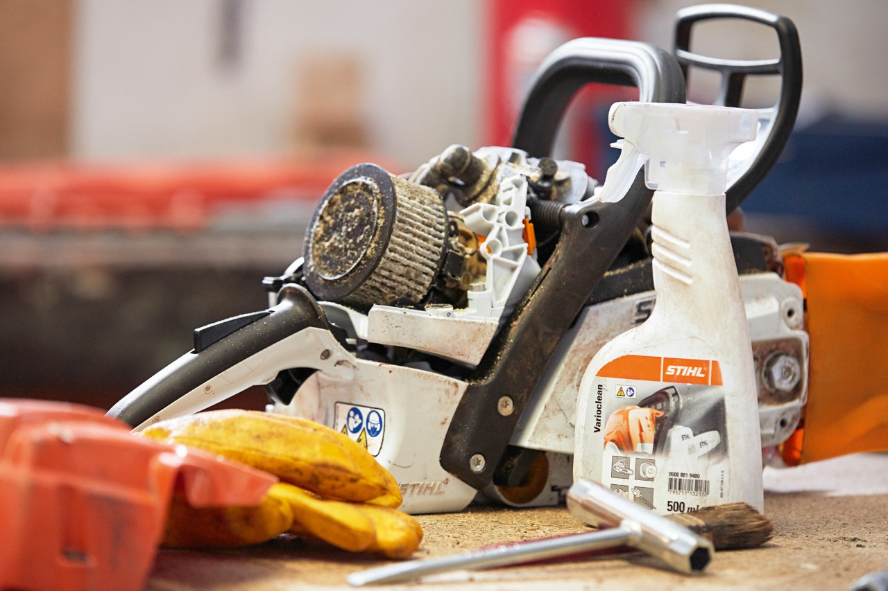 Një motosharrë STIHL mbi një tavolinë pune, me pastruesin STIHL Varioclean të vendosur përpara saj.