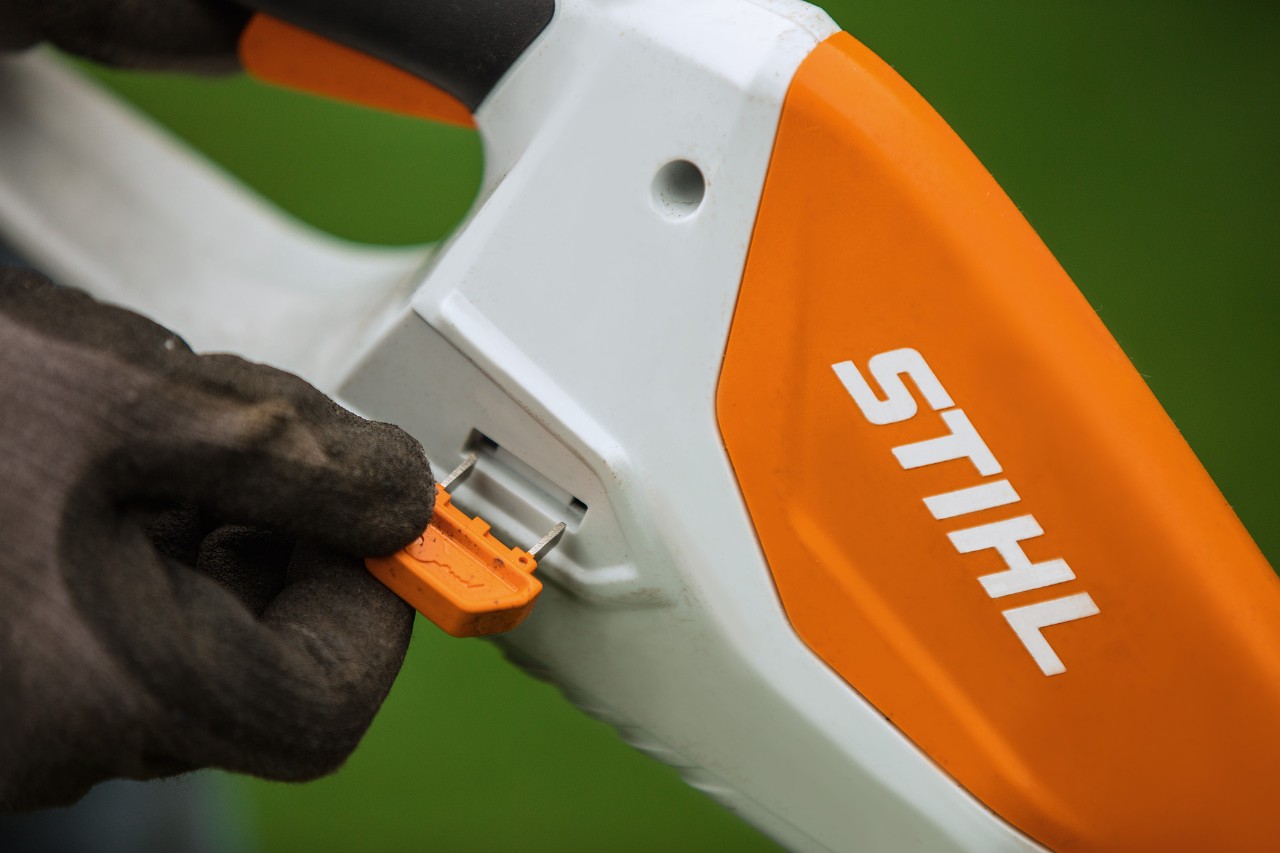 Pamje nga afër e çelësit të aktivizimit në trimer bari pa tel STIHL me bateri të integruar